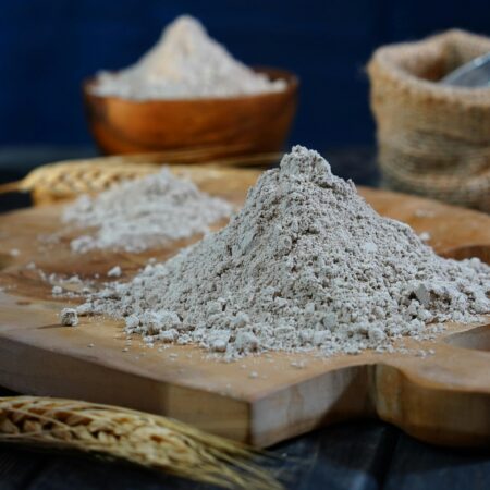 Close-up of flour on a wooden board with scattered grains for baking moods.